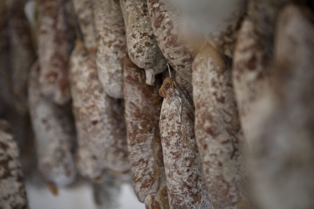 Gros plan sur une multitude de saucissons suspendus en train de sécher.