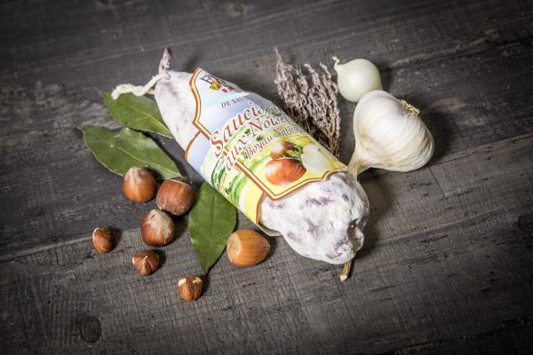 Saucisson aux noisettes présenté avec des noisettes, du thym et de l'ail